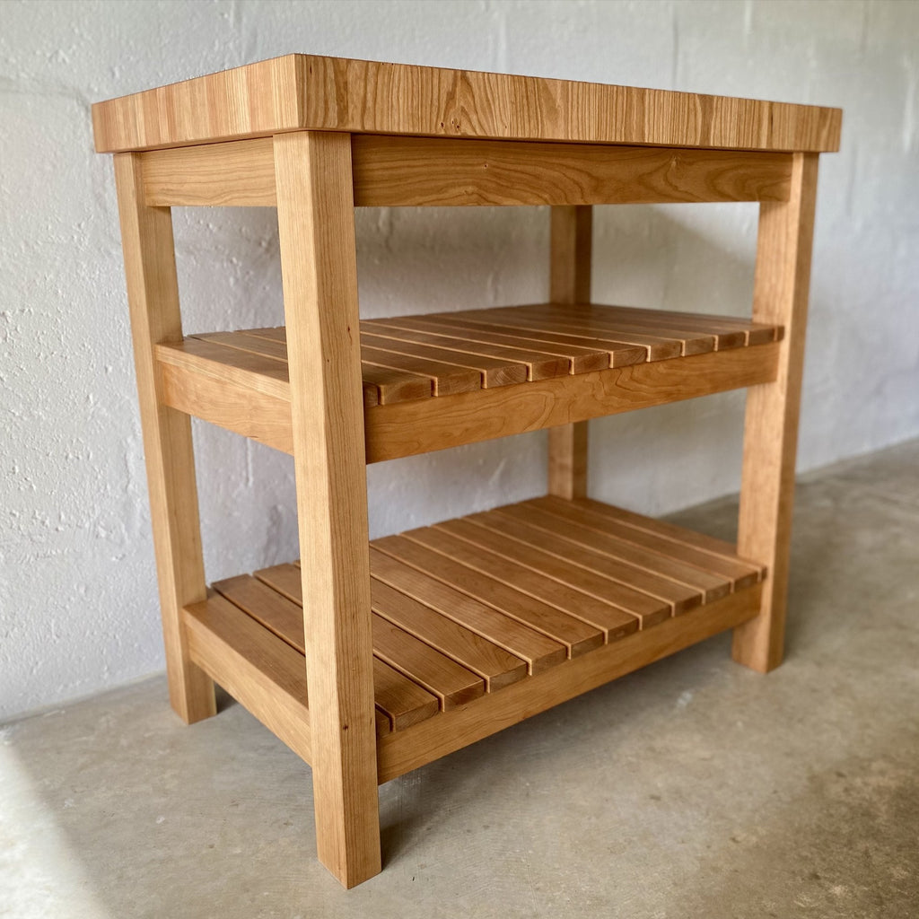American cherry end grain butcher's island with two slatted shelves, angled view against white wall – East Wood Design