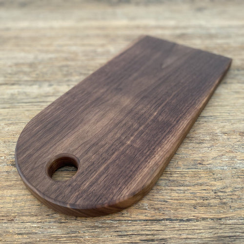 Black walnut arc platter teardrop shape angled view on rustic timber surface showing finger hole – East Wood Design