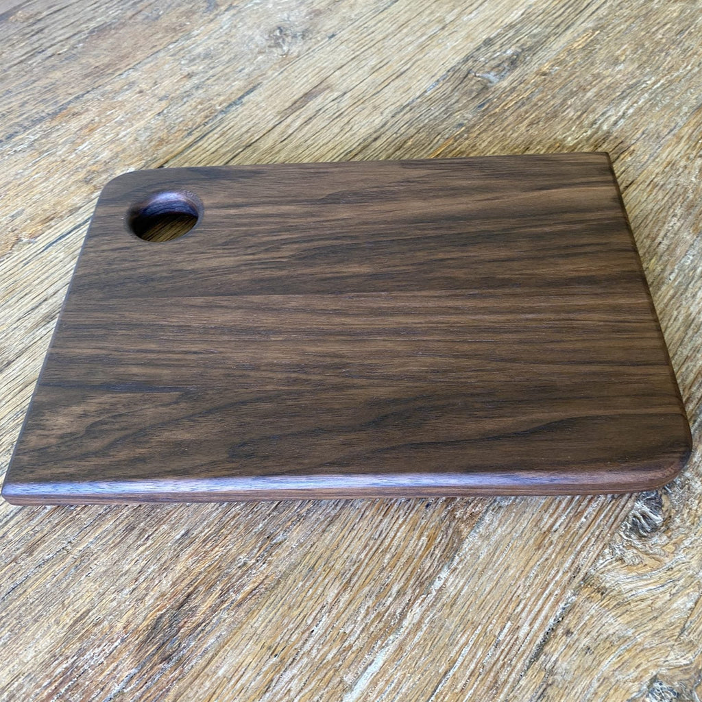 Small black walnut chopping board showing side profile and thickness on timber surface – East Wood Design