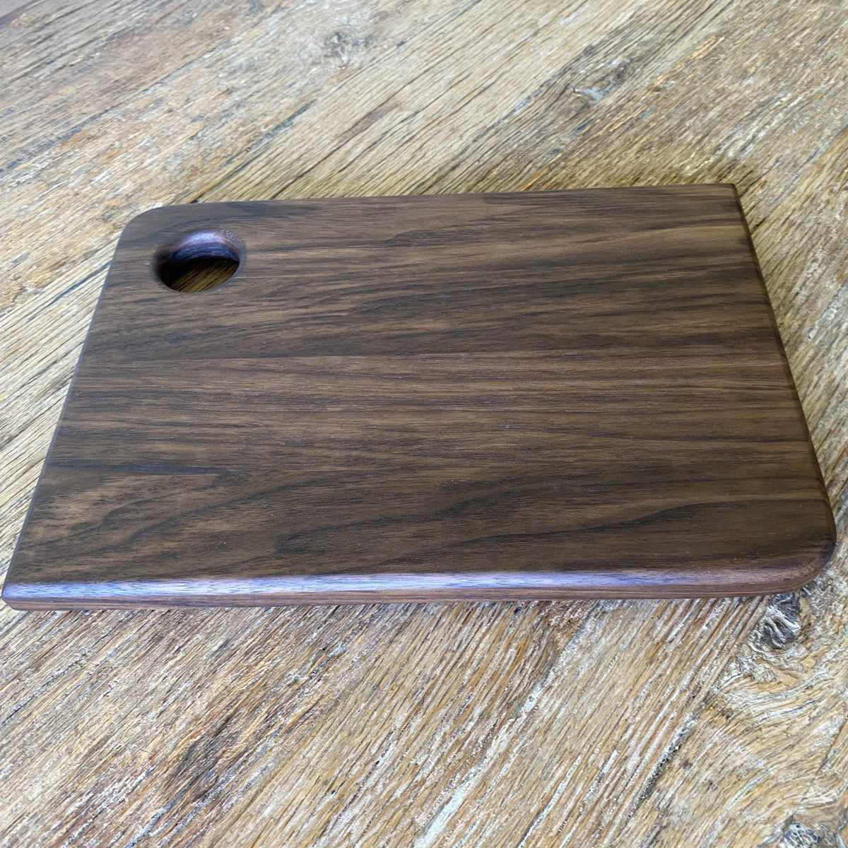 Small black walnut chopping board showing side profile and thickness on timber surface – East Wood Design