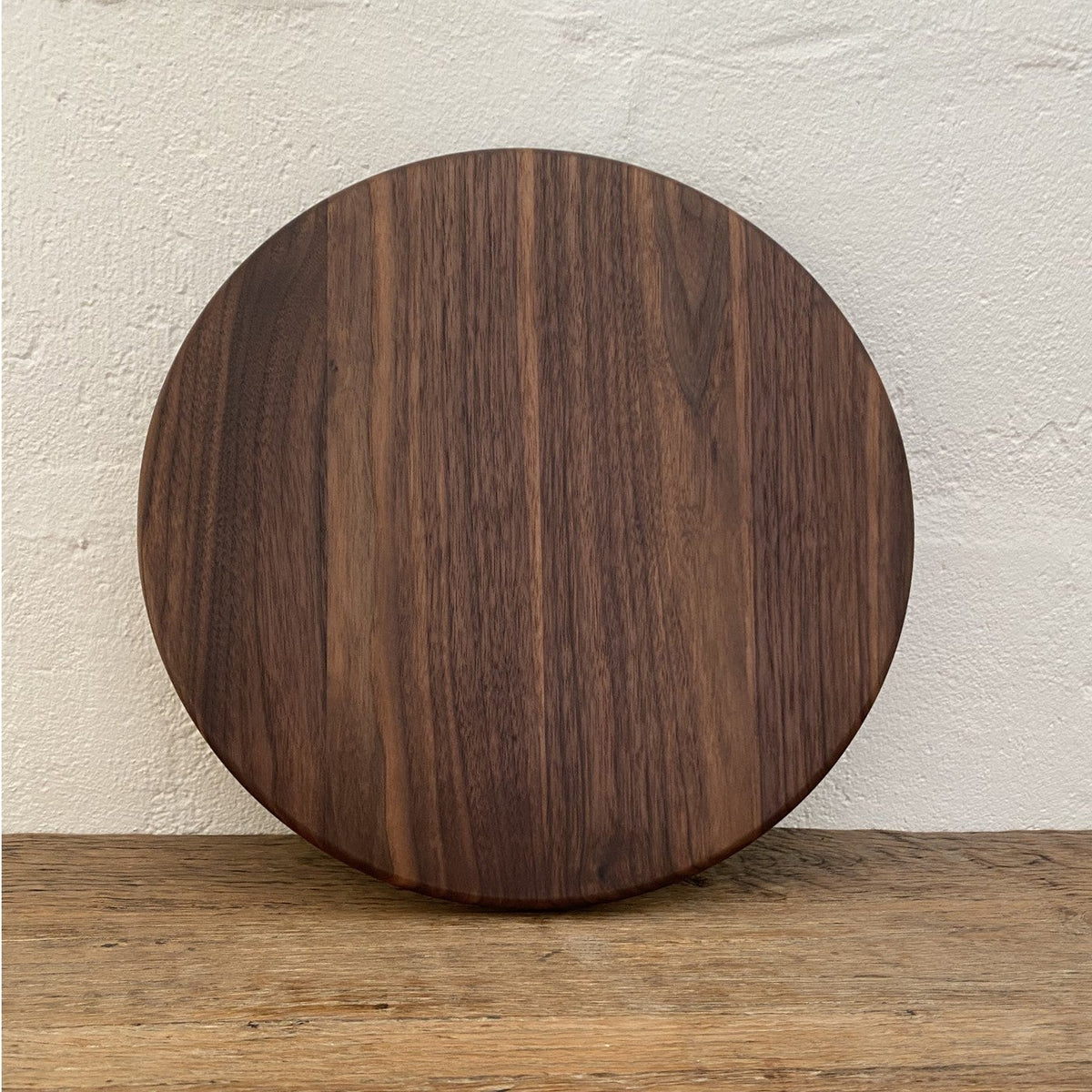 The Round Black Walnut serving board – angled lifestyle view on rustic timber surface