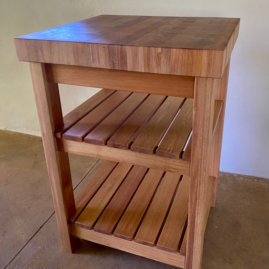 A end grain butcher island, made from pacific rimu with a middle slatted shelf, and a bottom slatted shelf, photographed in an indoor setting