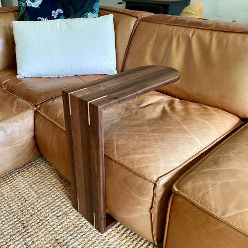 A  Black Walnut C side table, shown slid over a leather couch