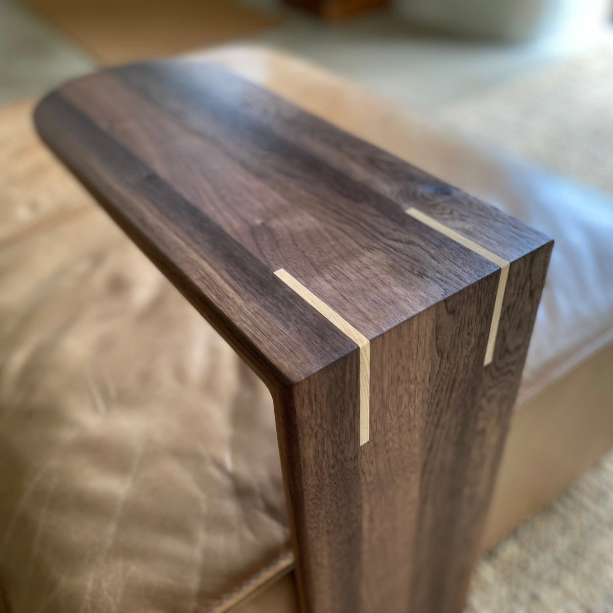 Close up view of a Black Walnut C side table with contrasting White Ash splines on the mitre join