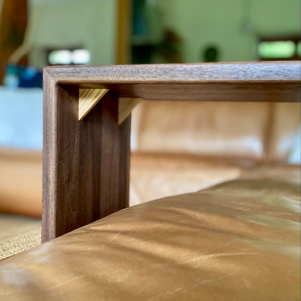 A close up of the underside of a Black Walnut C table showing the contrasting White Ash timber splines in the mitre join