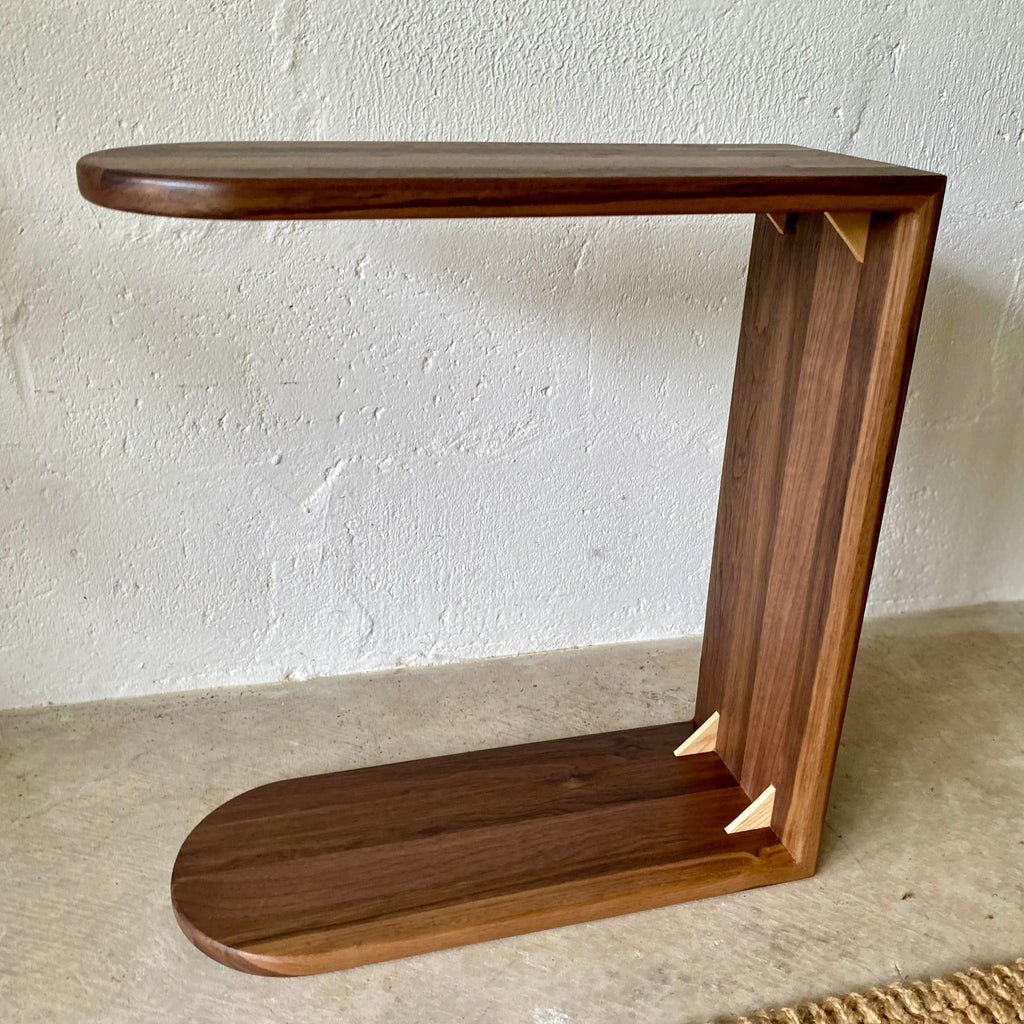 A Black Walnut C side table showing contrasting white timber splines on a concrete floor with a white wall behind
