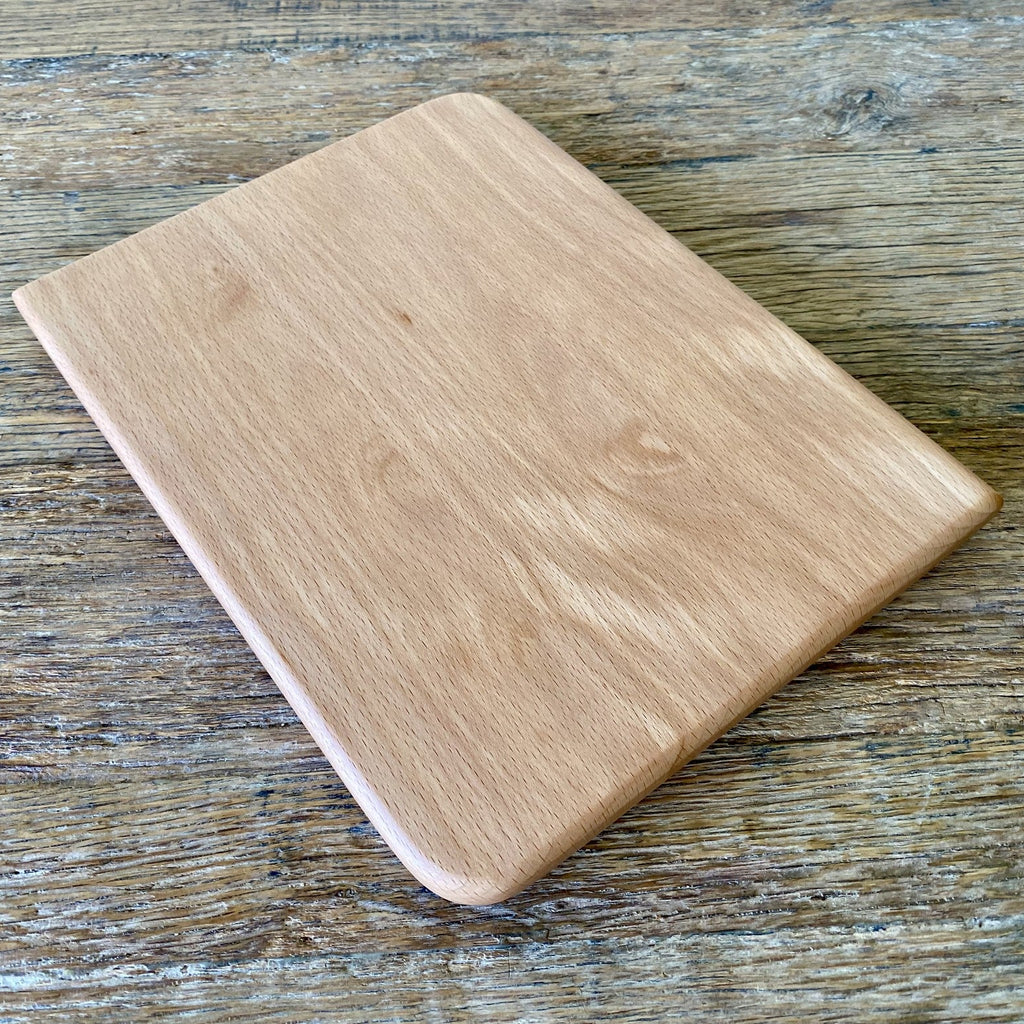 Small European beech chopping board angled view on rustic timber surface showing rounded edges – East Wood Design