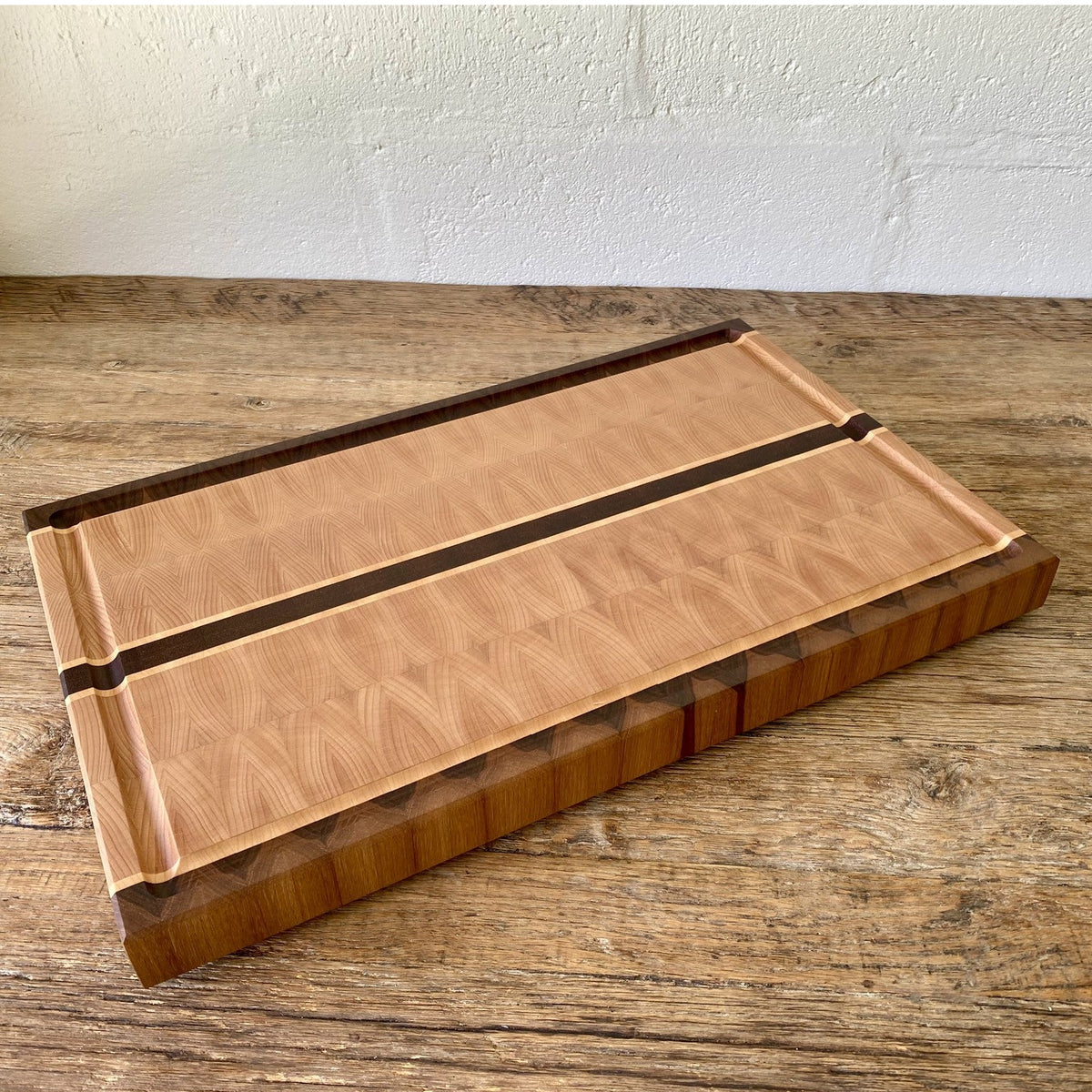 European Beech End Grain board – angled view showing end grain sides and walnut border on rustic timber surface