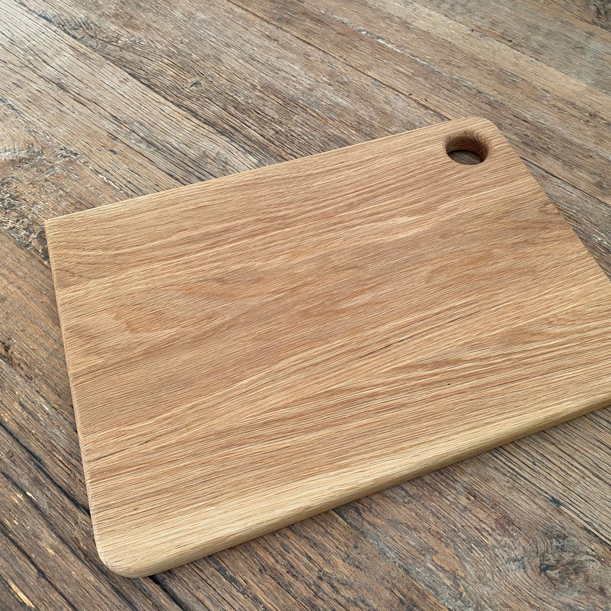 White Oak Chopper Board Large with finger hole— laying on a rustic surface 