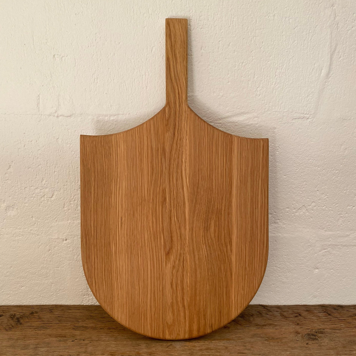 The Ray Board in American White Oak – front view leaning against white wall showing sting ray inspired shape and handle