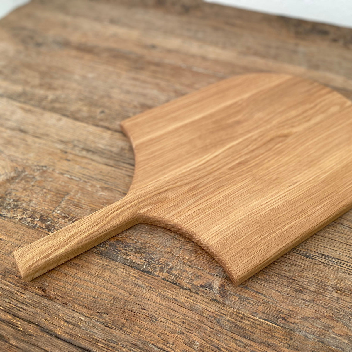 The Ray Board in American White Oak – top-down view on rustic timber surface showing warm golden grain