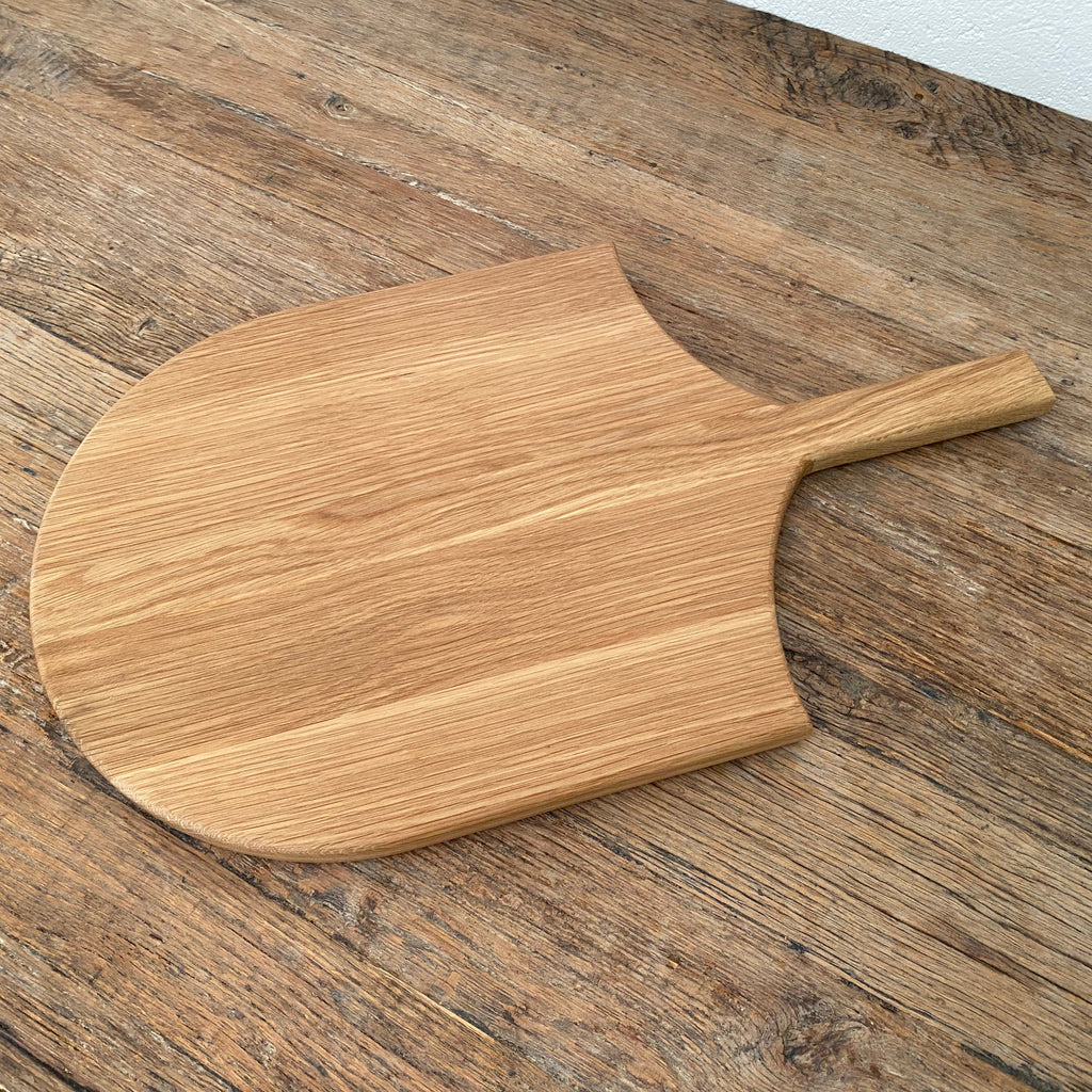 The Ray Board in American White Oak – angled view on rustic timber surface showing board profile and handle