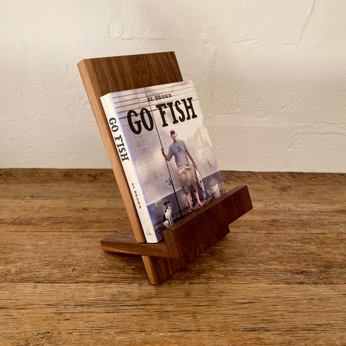 Book stand in Black Walnut holding a cookbook, angled view on rustic timber surface