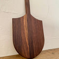 The Ray Board in American Black Walnut – front view leaning against white wall showing sting ray shape and handle