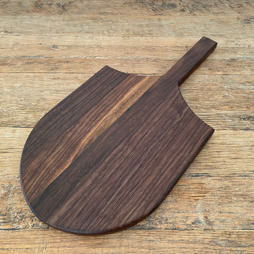 The Ray Board in American Black Walnut – angled top view on rustic timber surface showing rich grain detail