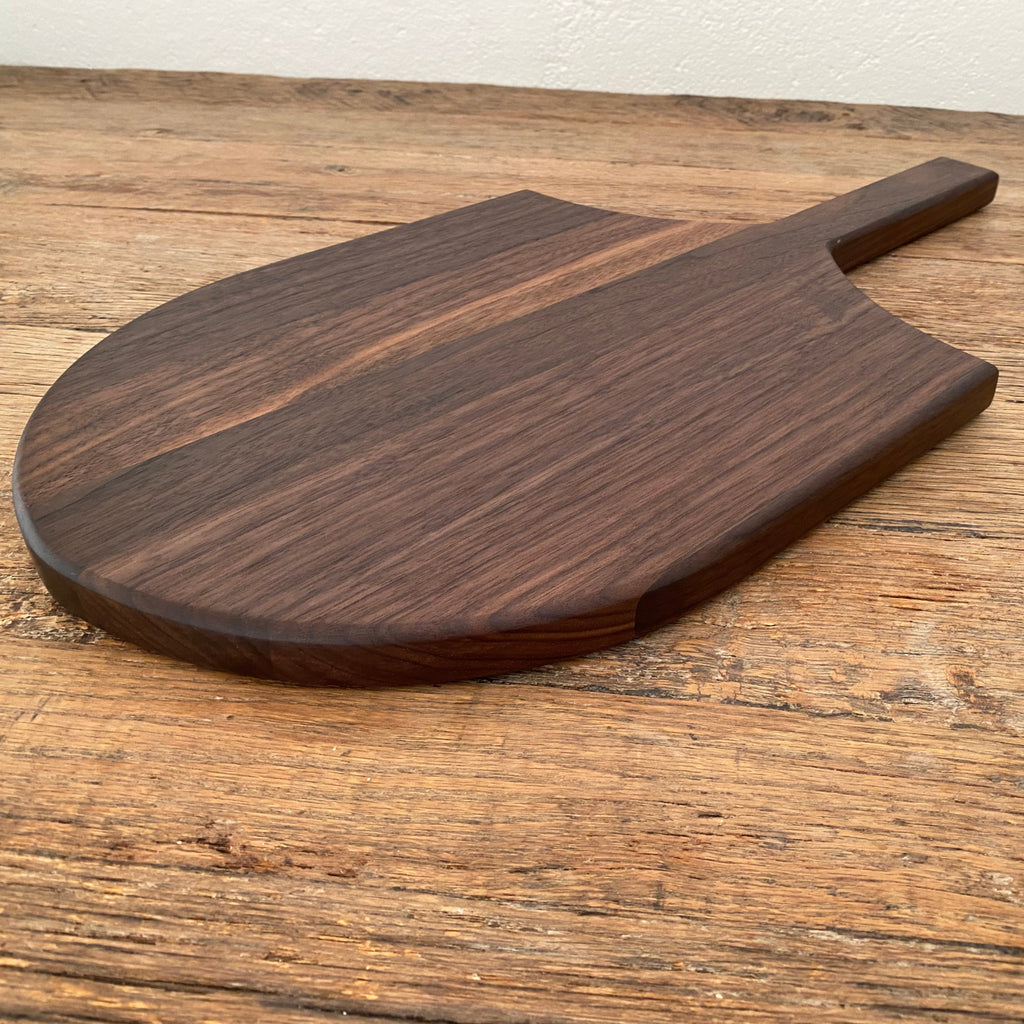 The Ray Board in American Black Walnut – side angle view on rustic timber surface showing board profile