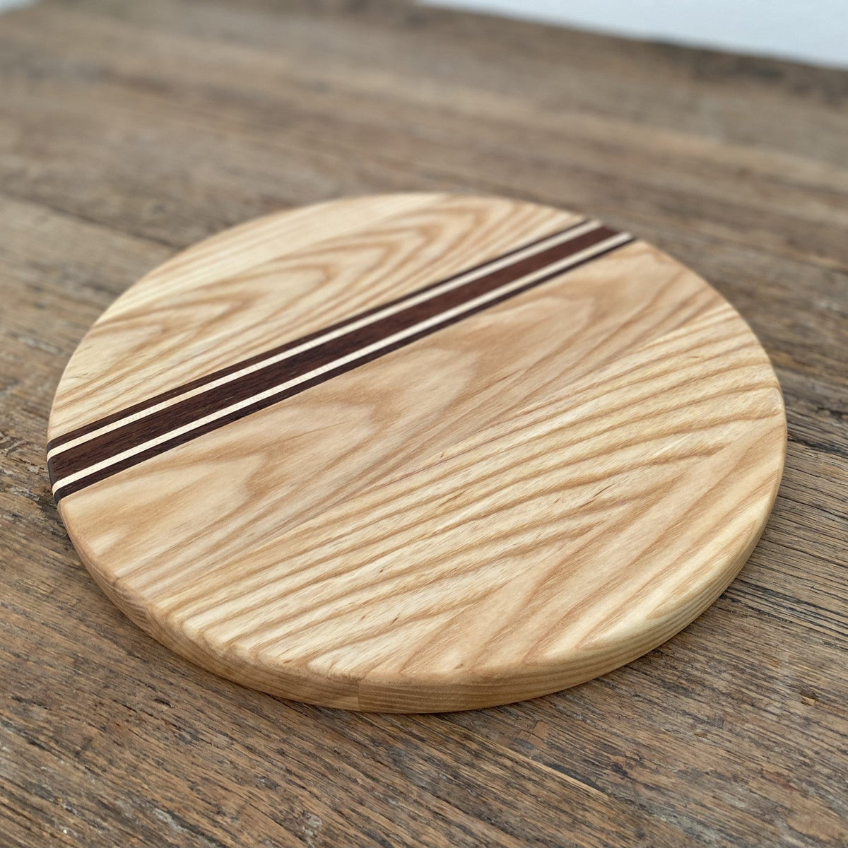The Rounds American Ash with Kwila and Maple stripe – angled top-down view on rustic timber surface