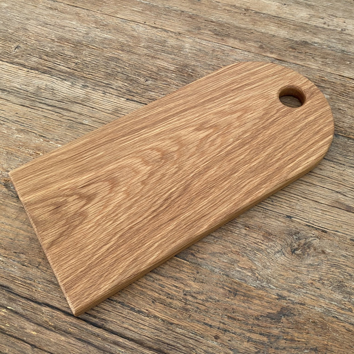 White oak arc platter tag shape angled view on rustic timber surface showing grain and finger hole – East Wood Design