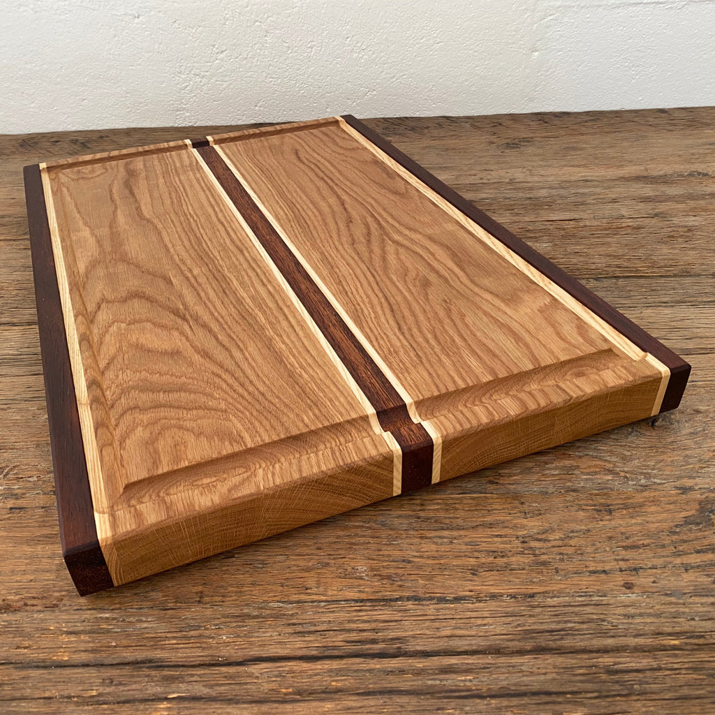 The Carver Grande chopping board in White Oak, Kwila and Maple – angled top view showing full board surface and accent stripes
