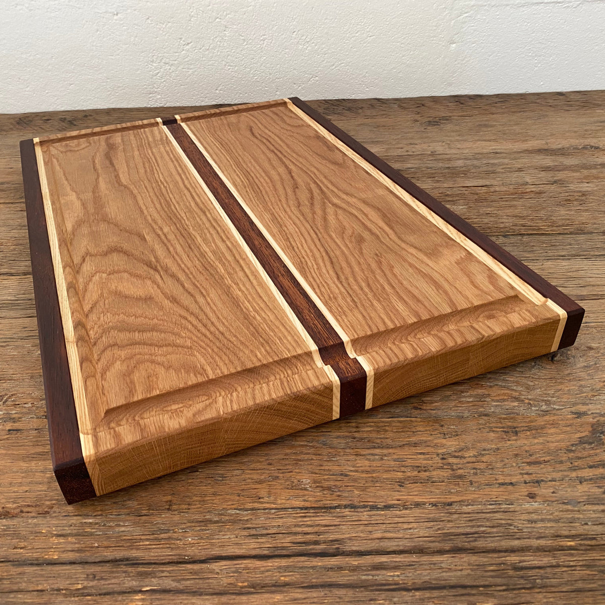 The Carver Grande chopping board in White Oak, Kwila and Maple – angled top view showing full board surface and accent stripes