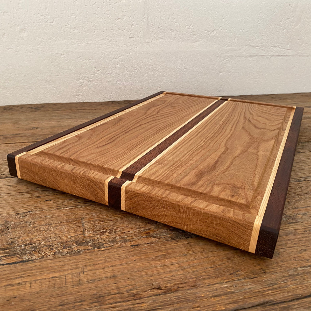 The Carver Grande chopping board in White Oak, Kwila and Maple – low angle side view showing 35mm thickness and stripe detail