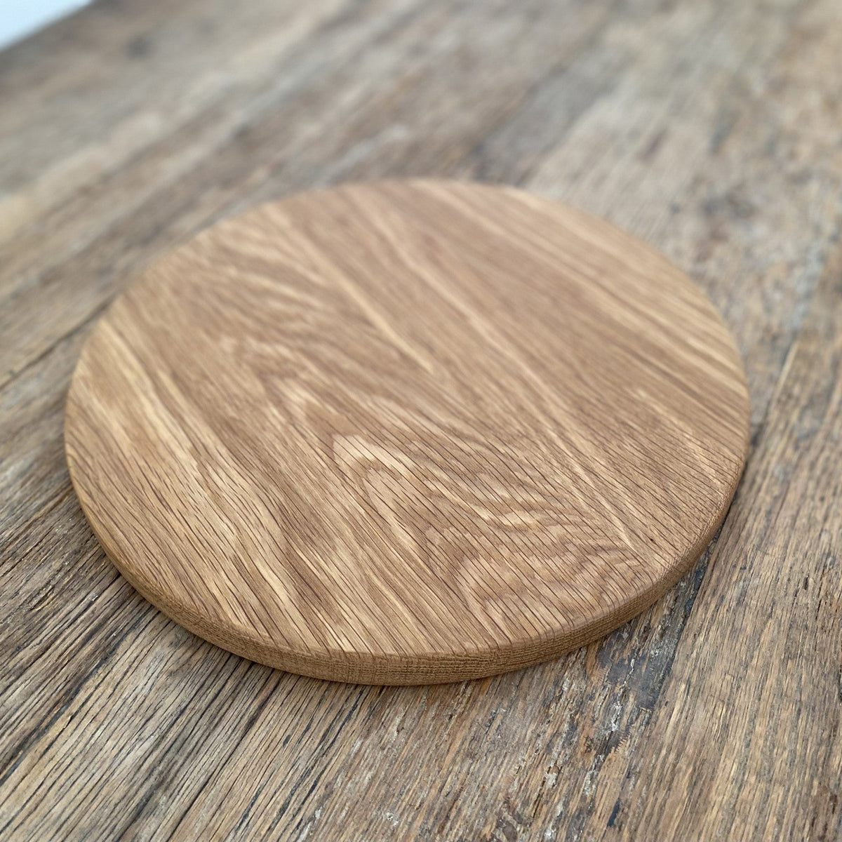The Round White Oak serving board – angled lifestyle view on rustic timber surface